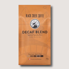 Orange coffee package labeled 'Black Creek Coffee Decaf Blend' on a light gray background
