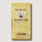 Yellow package of Black Creek Coffee Yellow Lab espresso blend on a light gray background